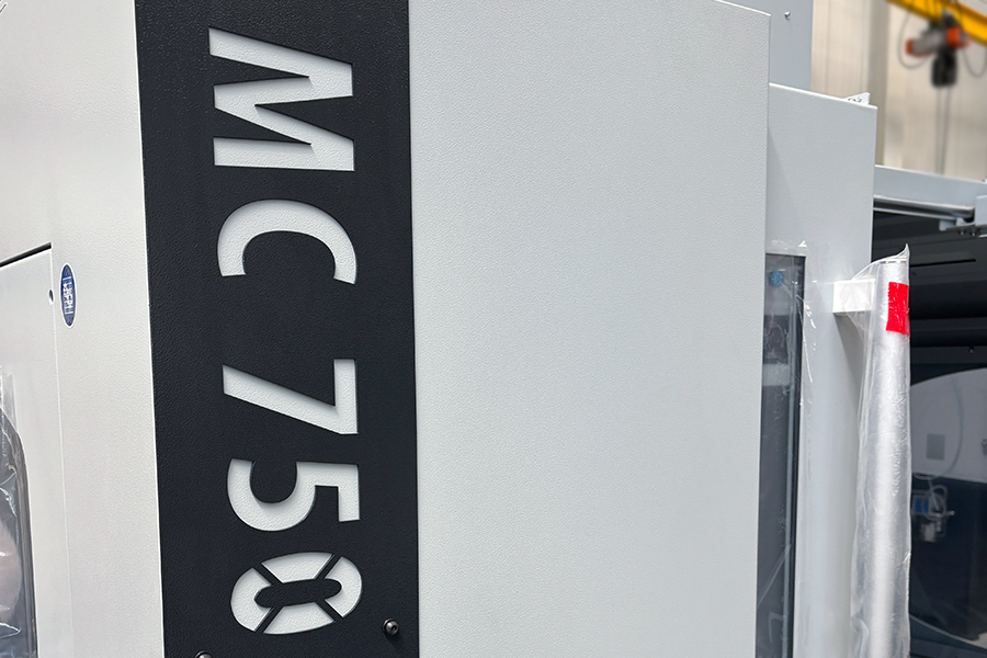 Detail CNC frézovacího centra MC 750 s označením modelu a robustní konstrukcí krytu